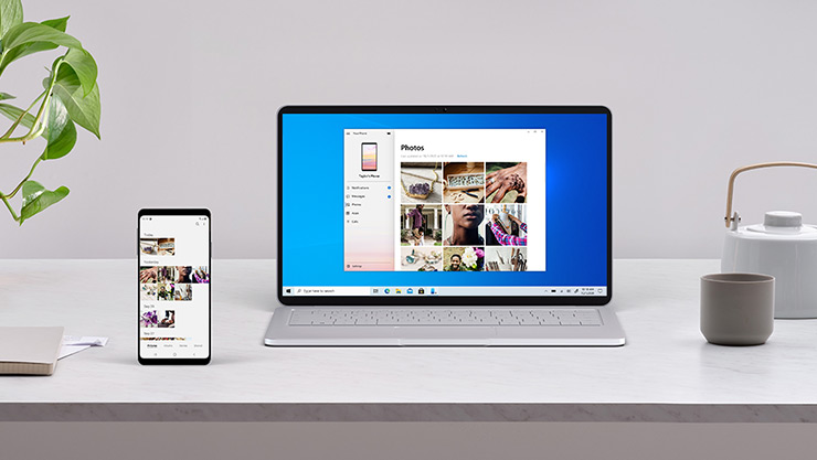 A Windows PC showing photos on the PC and the phone sitting next to it using the Phone Link app