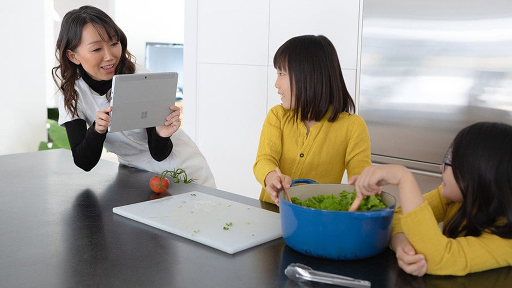 Mother taking a picture of children cooking with Surface Go