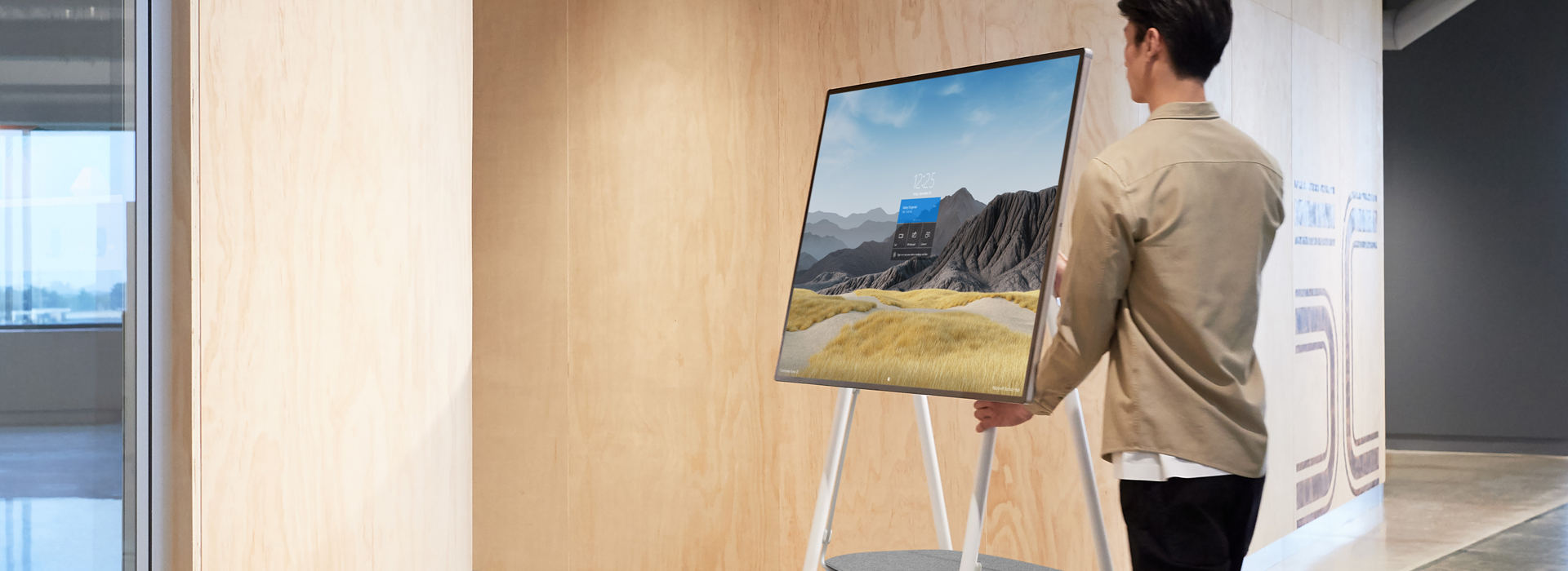 A man transports Surface Hub 2S on a mobile rolling stand