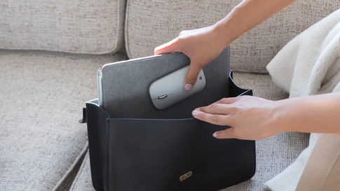 A woman puts Surface Go and Surface Mobile Mouse in her purse