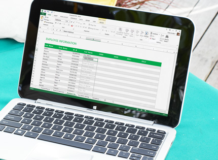A laptop showing a rearranged Excel spreadsheet with data auto-completed.