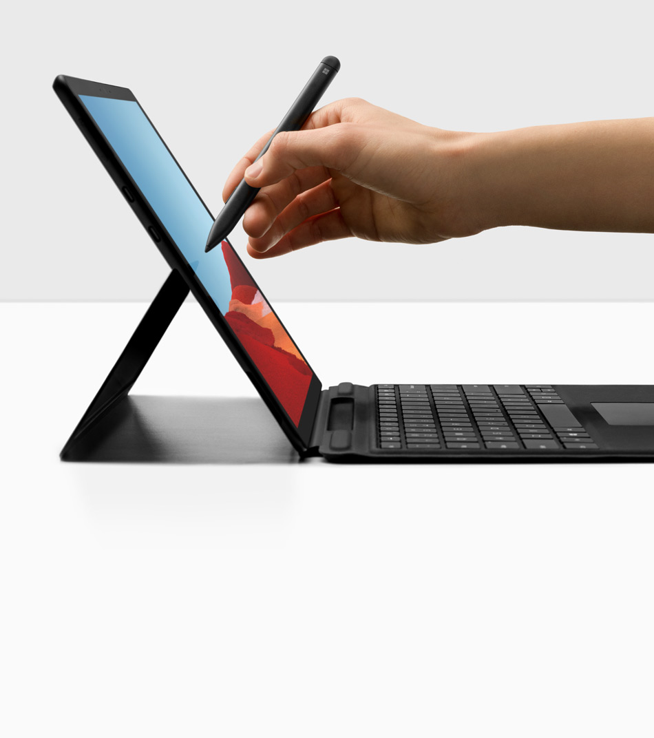 Una mano scrive con la penna Surface Slim Pen su un computer Surface Pro X