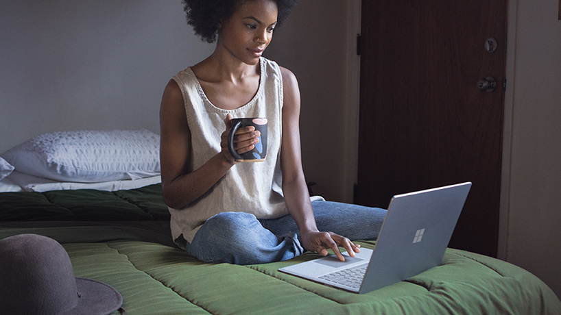 Una donna su un letto lavora con Surface Laptop.
